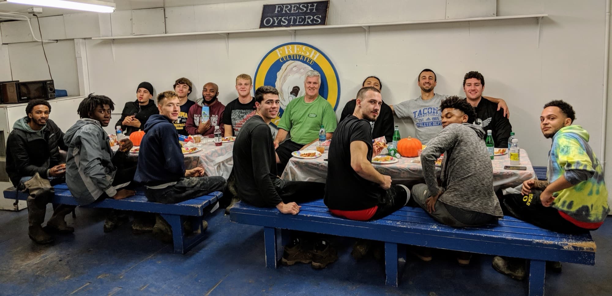 A crew of young workers gathered around picnic tables in the Minterbrook shucking room after a work day