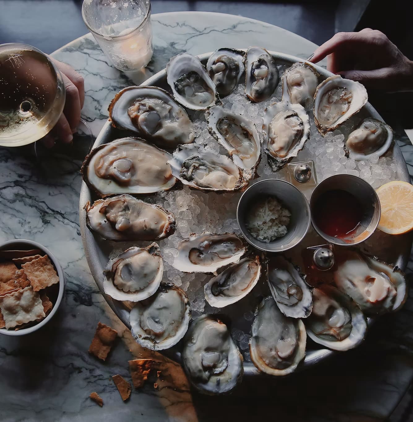 A restaurant platter of Minterbrook oysters on the half shell over crushed ice, with mignonette, lemon, and wine